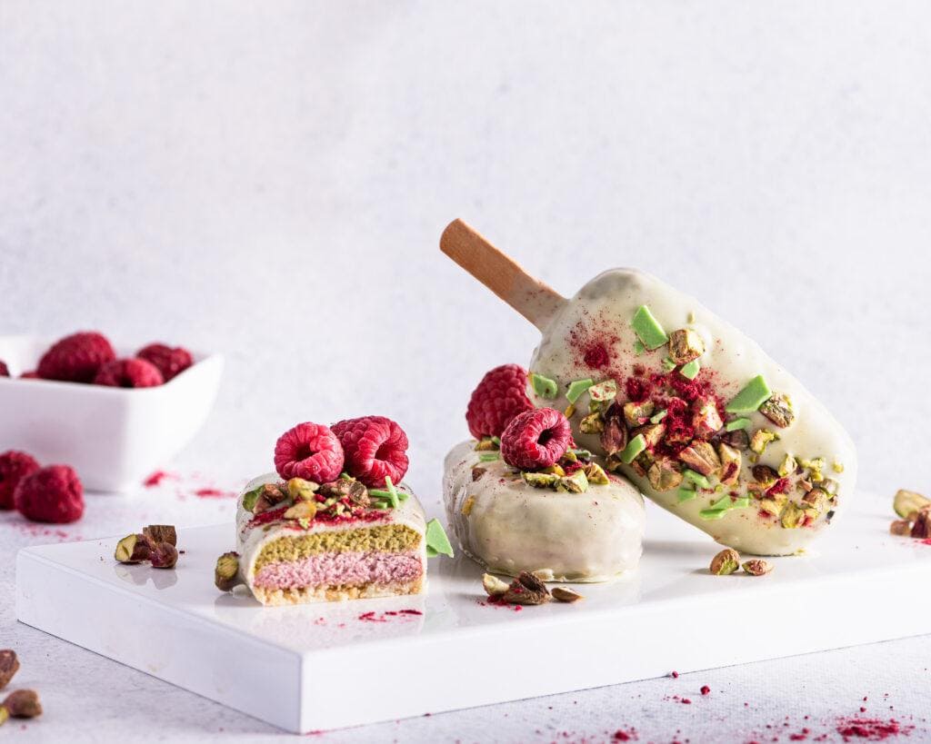 Ice cream sticks with white chocolate, fruit, pistachios and colored sugar on a white background