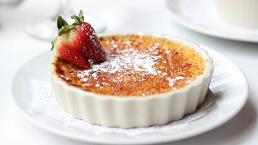 creme brûlée with powdered sugar and a strawberry