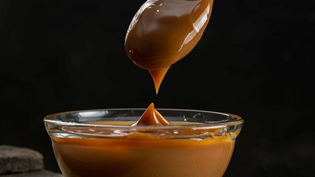 Close-up of caramel being poured into a glass bowl for sweet recipes.