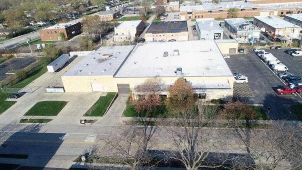 Aerial view of a commercial building with parking lot and surrounding area.
