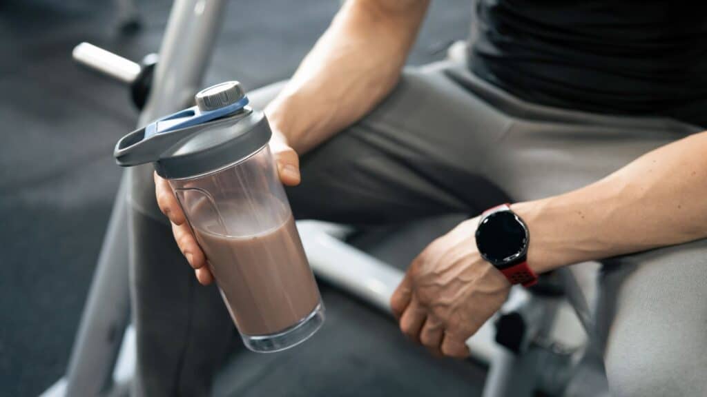 A healthy person holding a protein shake after workout at gym.