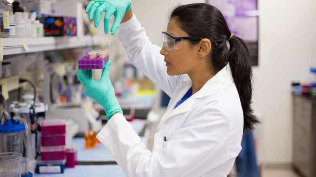 Scientist handling test tubes in a laboratory setting for sugar research.