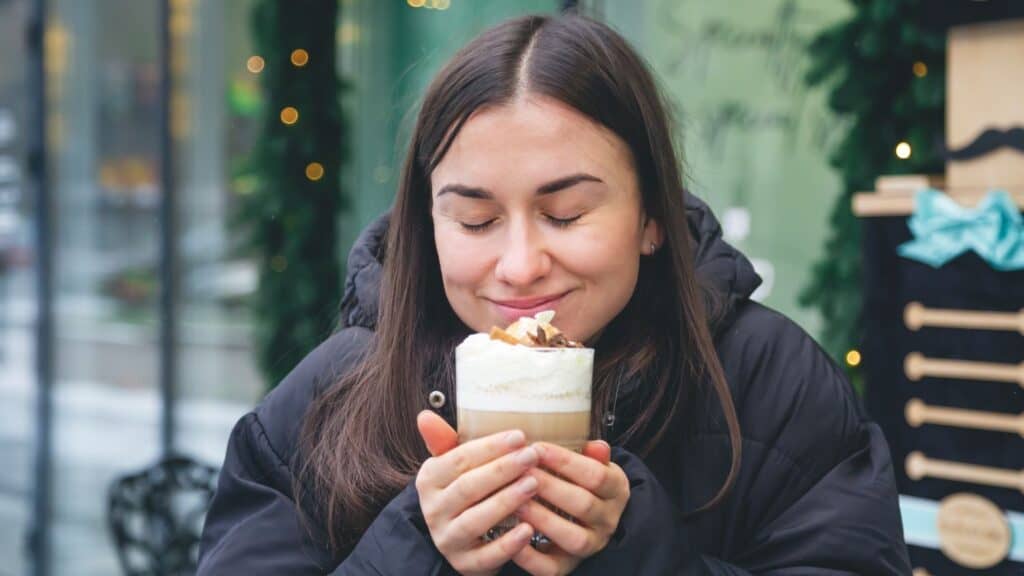 Woman enjoying a hot beverage in a cozy cafe setting.