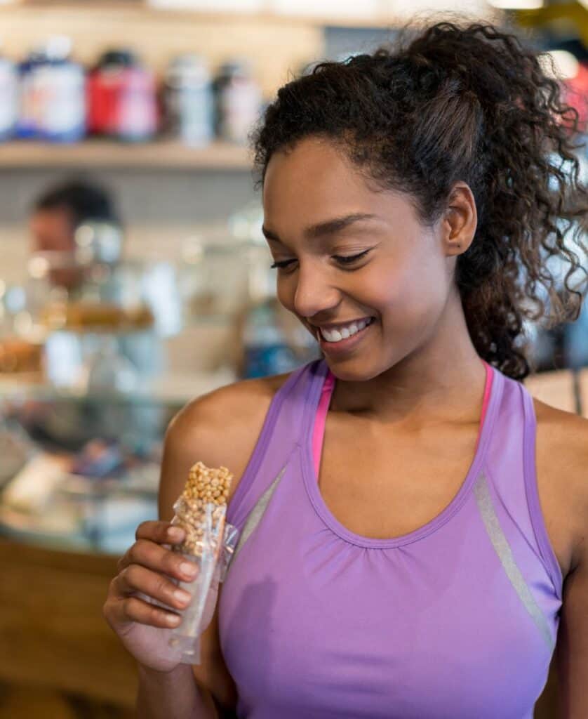 Woman eating a protein bar, illustrating bitterness masking technologies in food and beverage